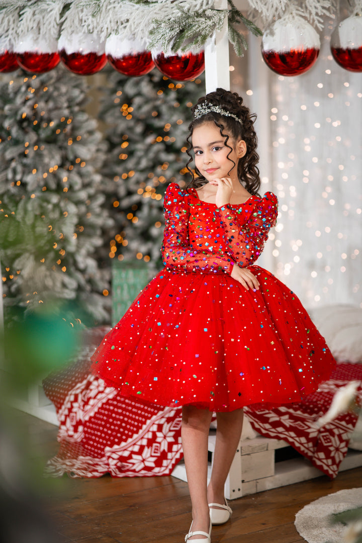 Young girl in a red dress with sequins standing in a festive setting with Christmas decorations.