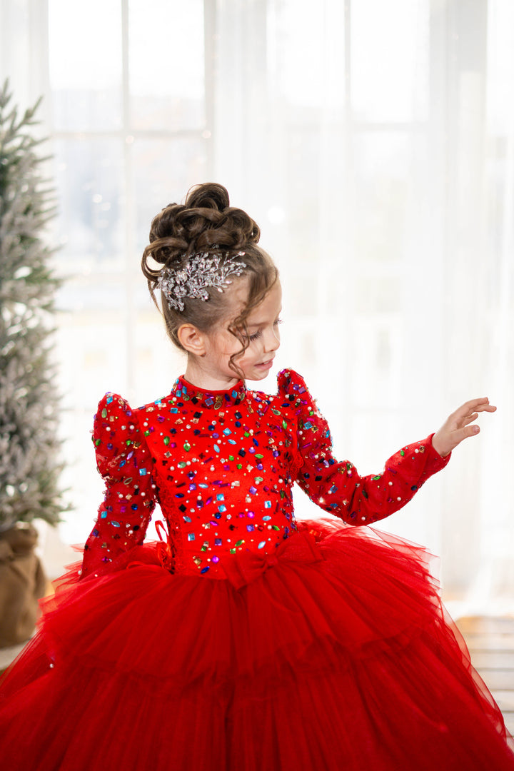 Child in a red dress with sequins and a tulle skirt, standing in a softly lit room.