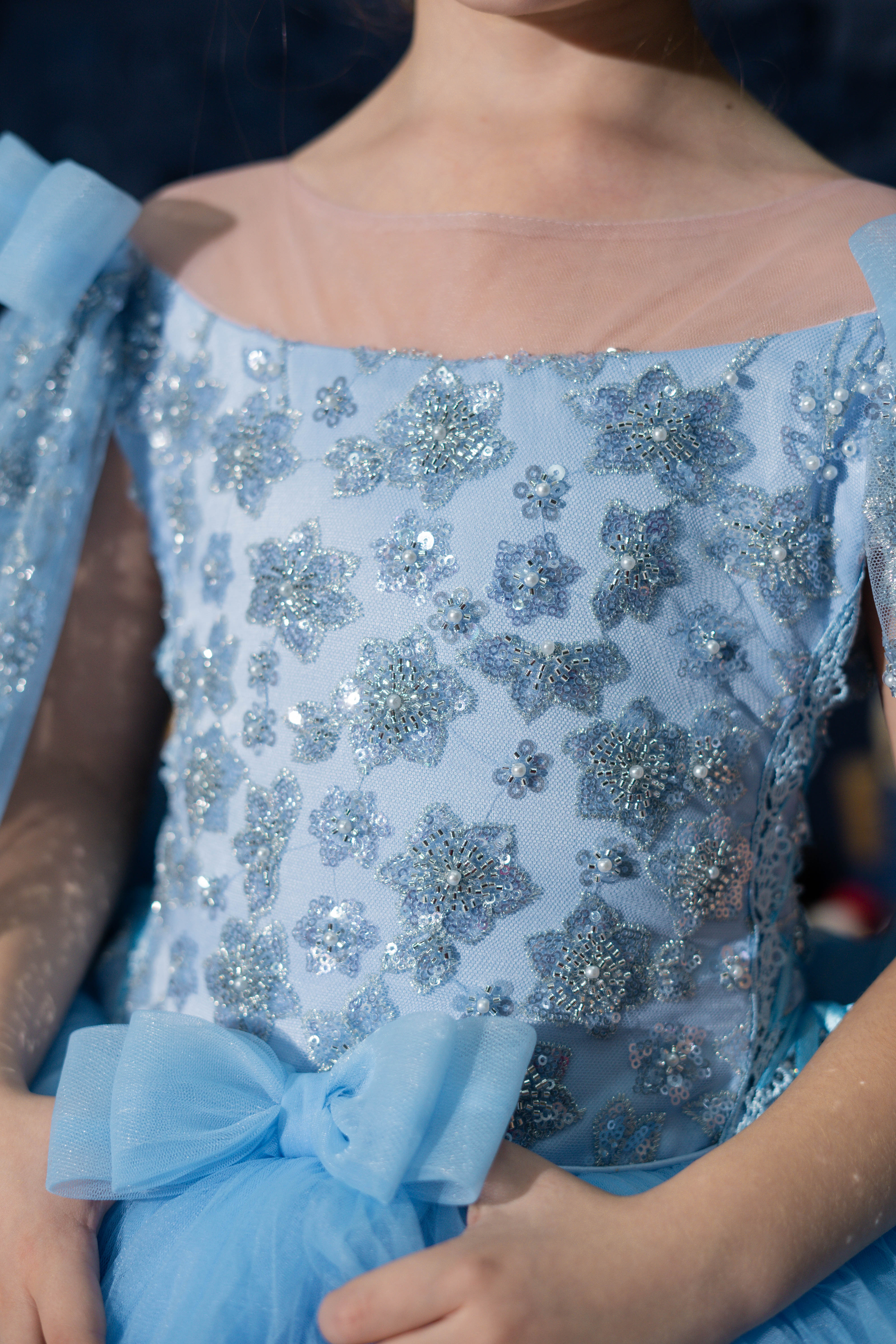 Close-up of a blue dress with floral patterns and a bow detail.