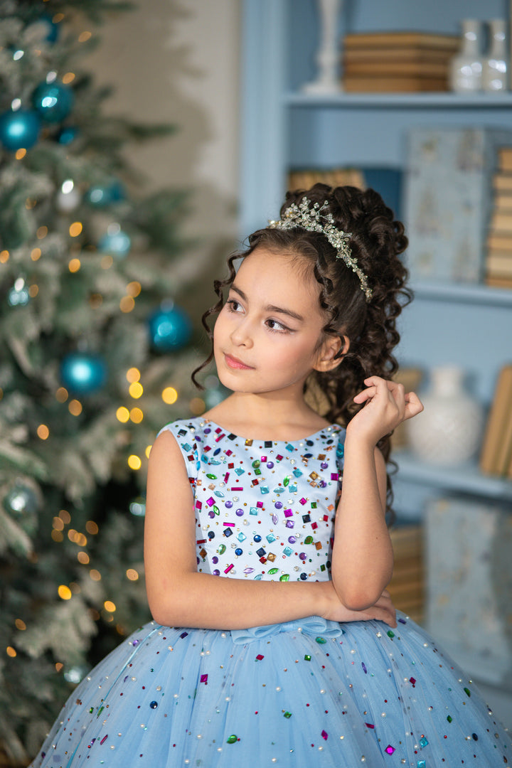 Young girl in a festive setting with a decorated tree and shelves in the background