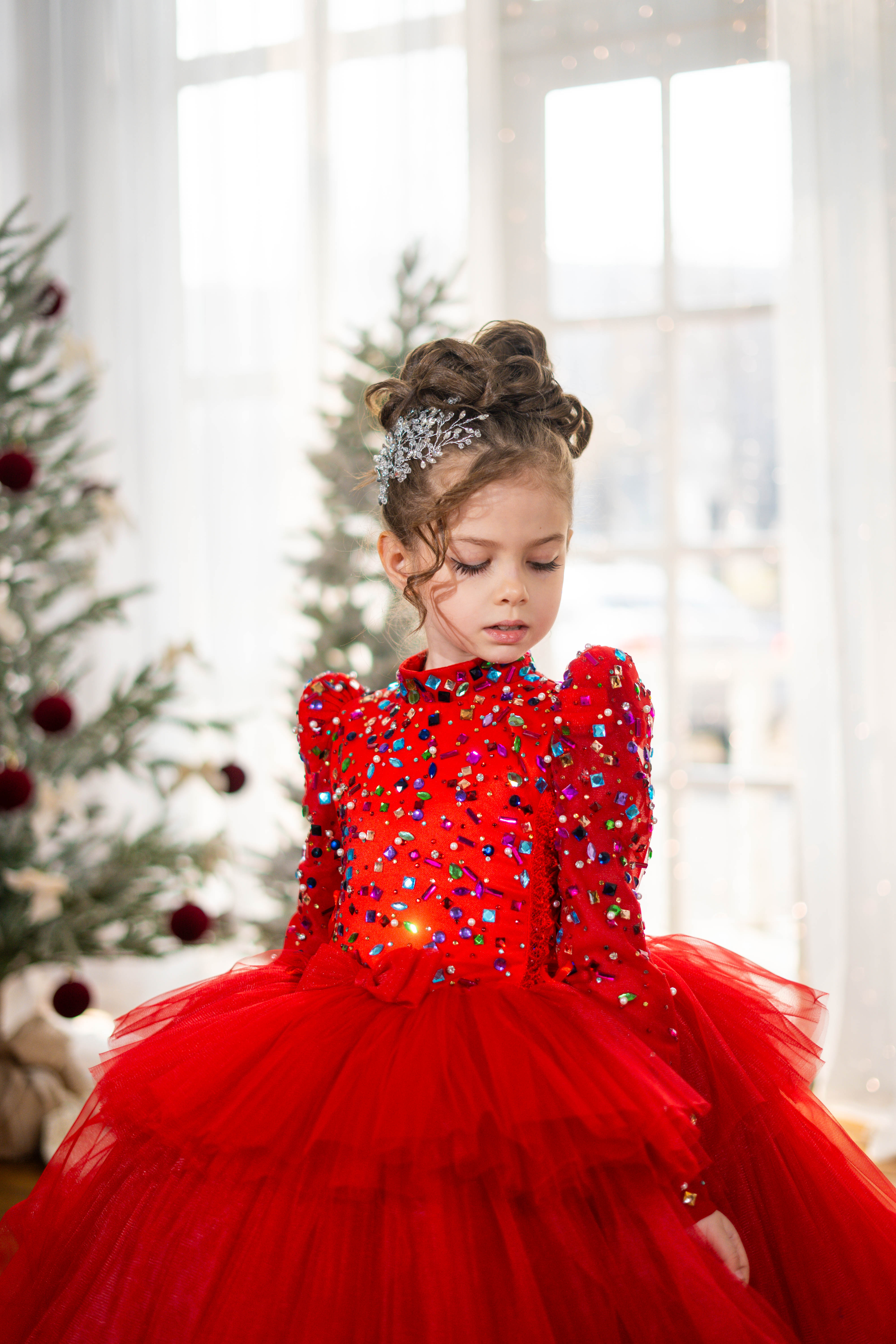 Baby girl in a red dress with sequins and tulle skirt in a festive setting.