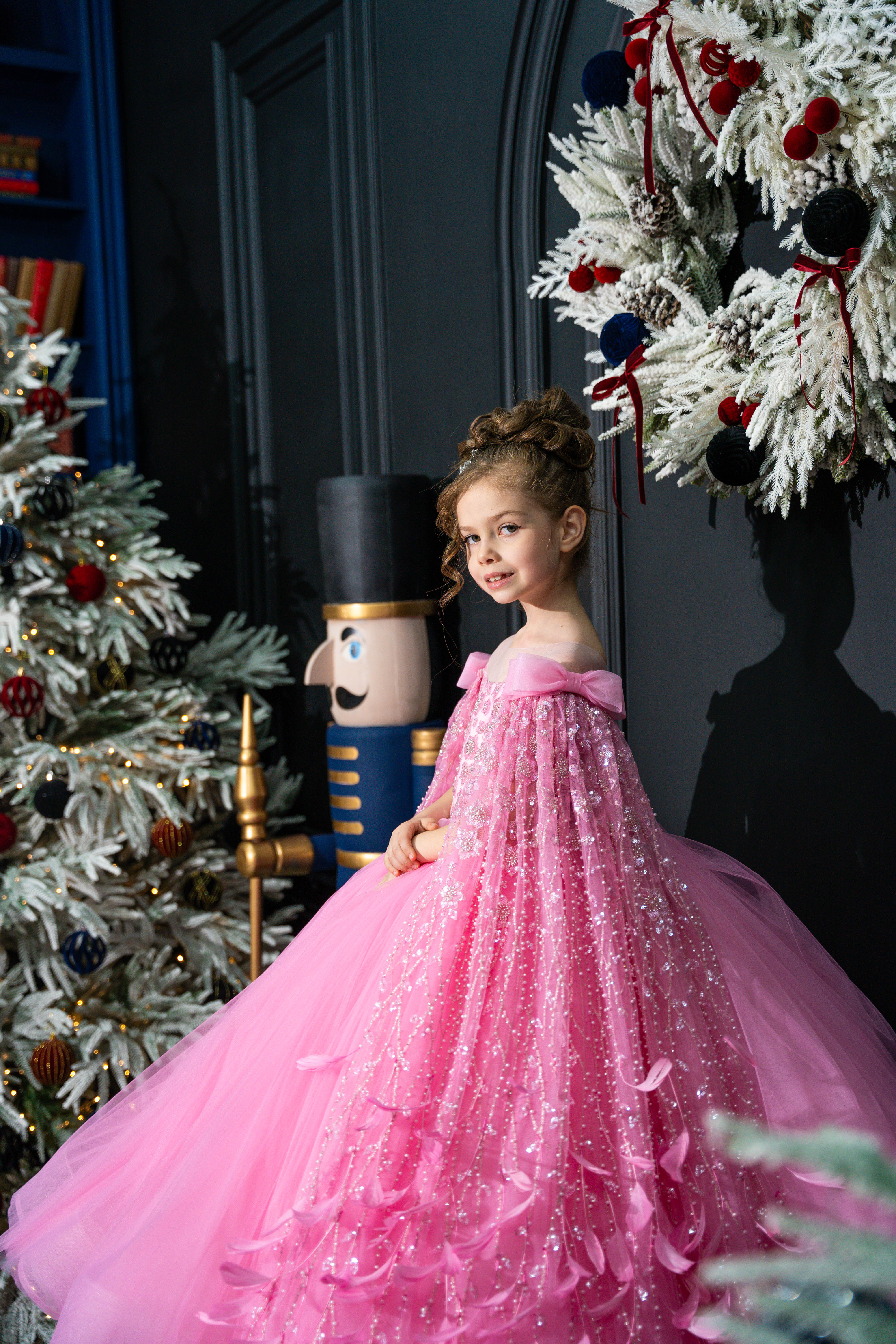 Young girl in a pink dress standing in front of Christmas decorations